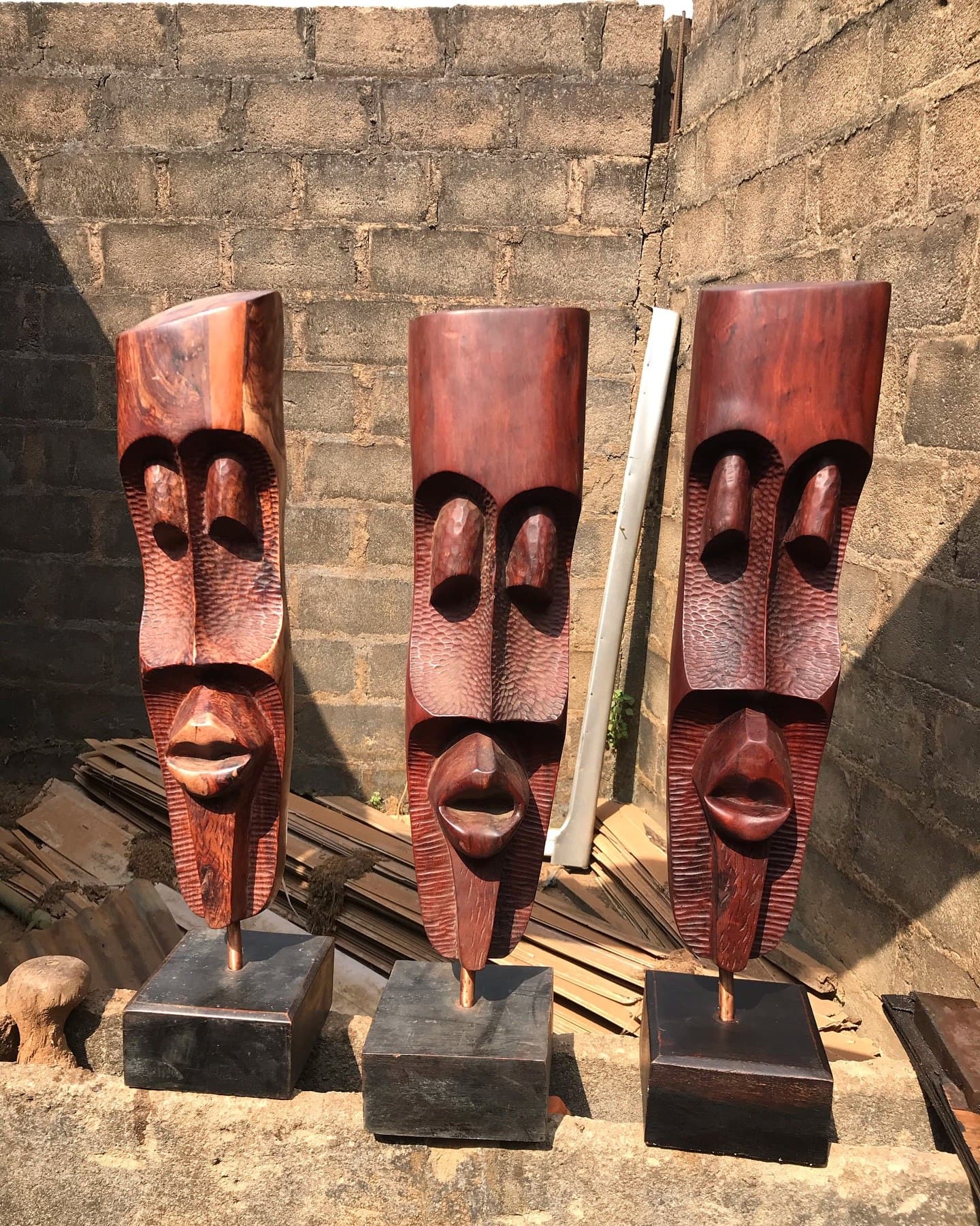 Three tall hand-carved wooden masks on display stands